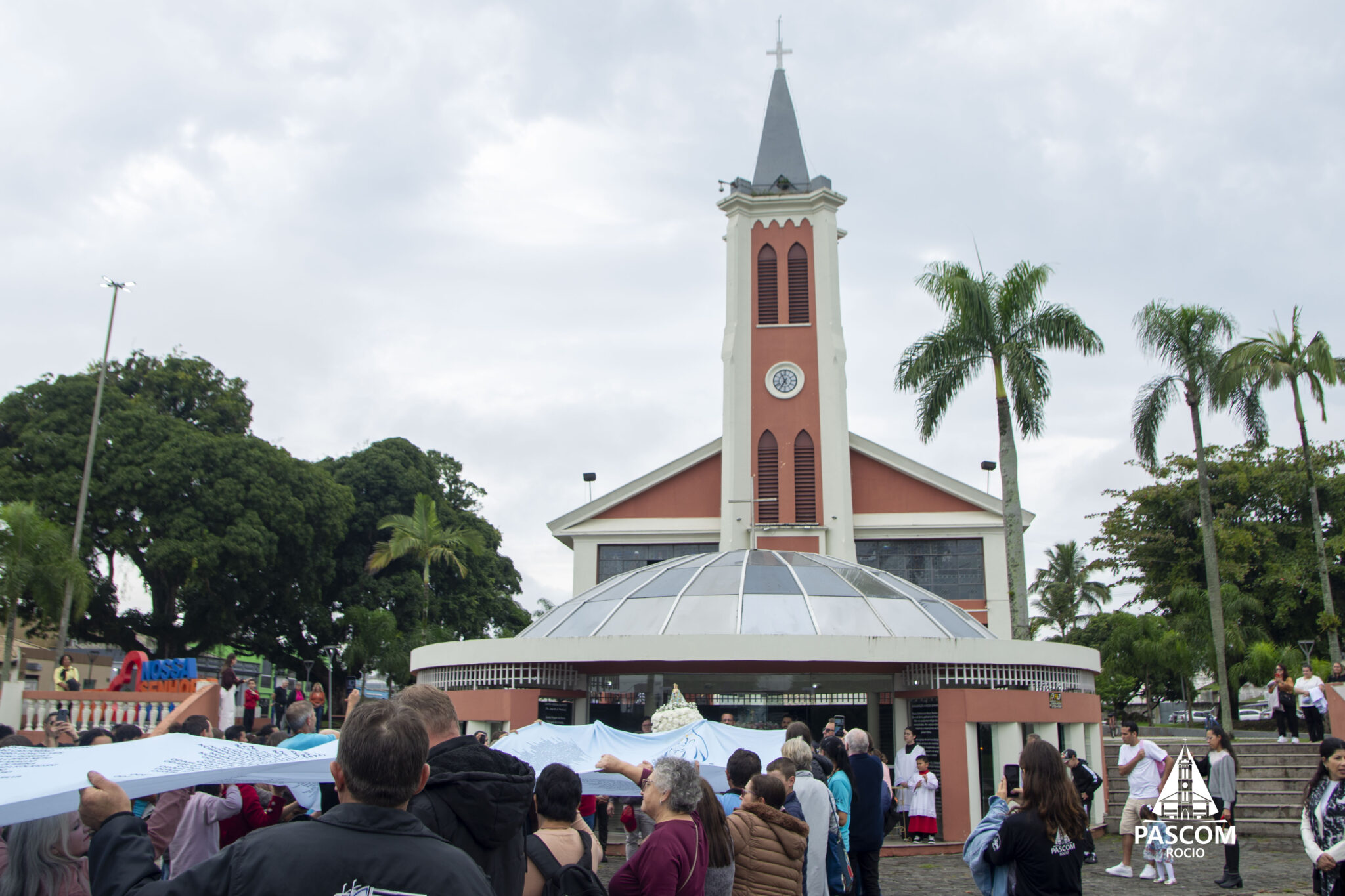 Romeiros na Praça da Fé carregam o manto enquanto realizam suas orações.