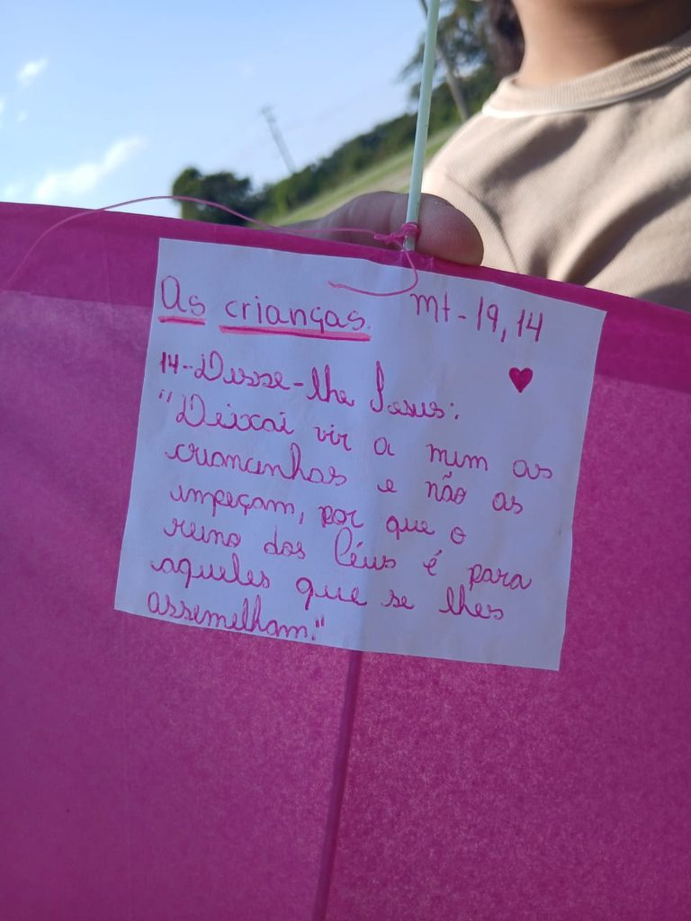 Detalhe de versículo bíblico escrito à mão em pipa para a Revoada da Catequese.